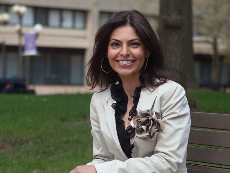 Dr. Saray Stancic sitting on a park bench in the city