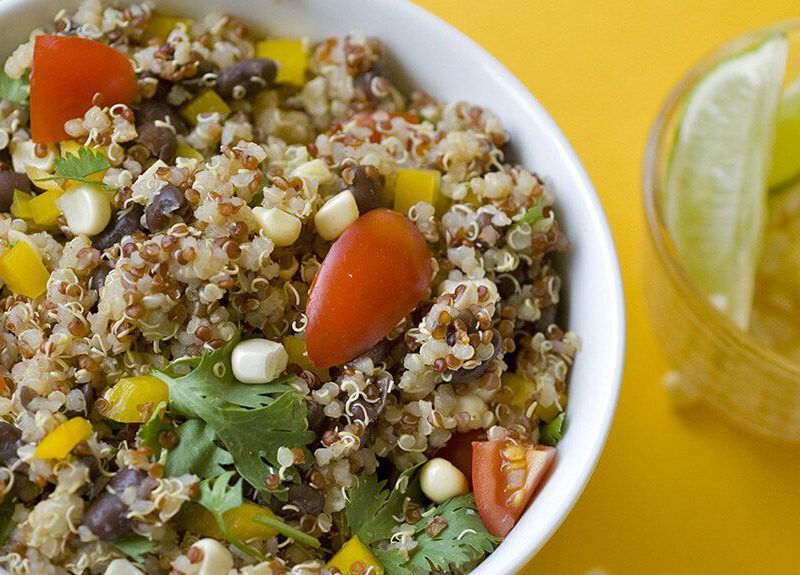 Fiesta Quinoa Salad in a white bowl with lime wedges in a smaller bowl