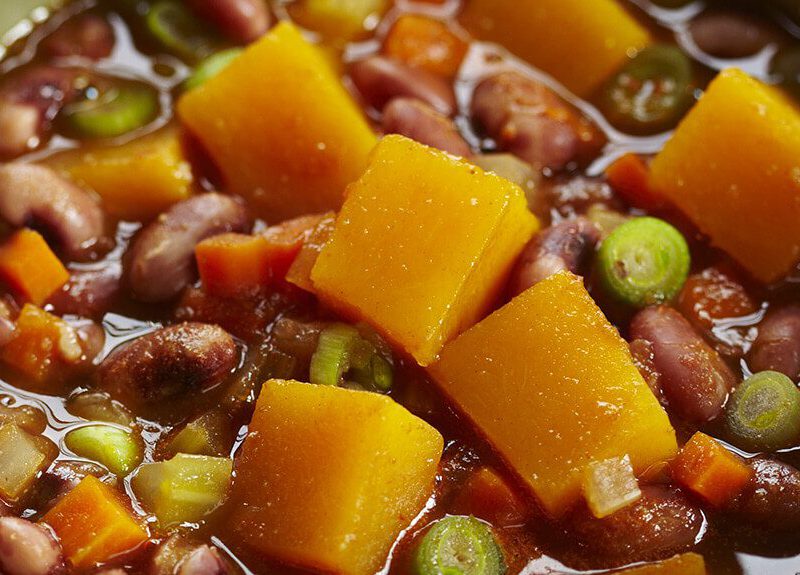A close-up of Pumpkin and Anasazi Bean Stew in a green bowl