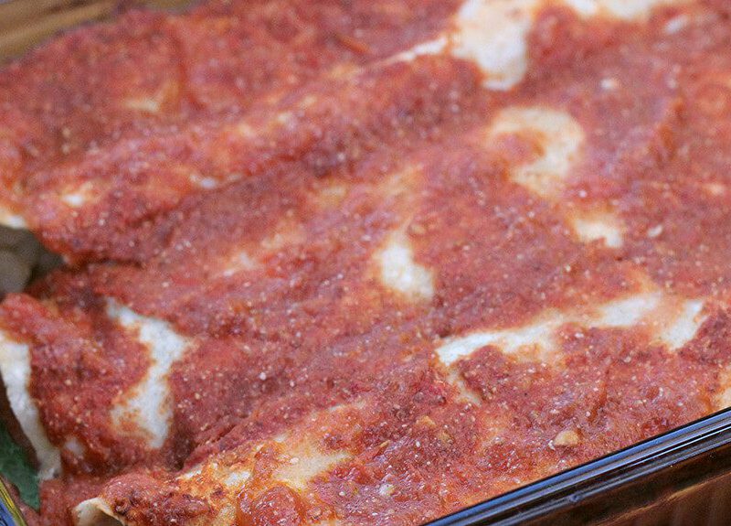 A glass casserole dish filled with three Plant-Based Potato Enchiladas