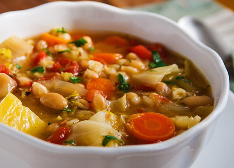 Irish White Bean and Cabbage Stew in a white bowl sitting on a white plate