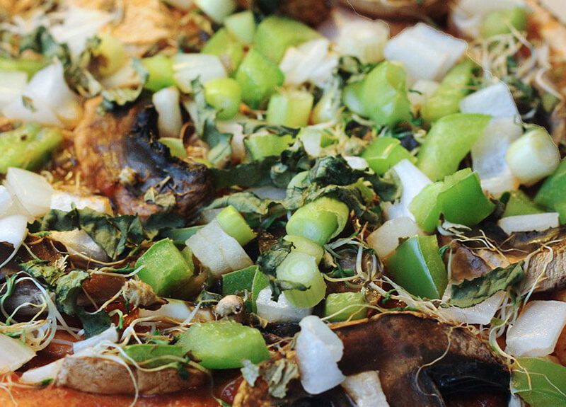 A pita bread pizza topped with green bell pepper, sprouts, mushrooms, and onion. Aka, "Fast Pizza"