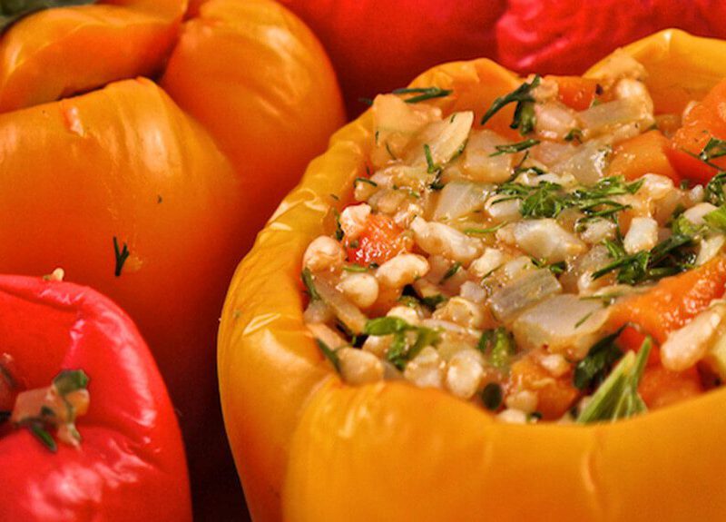 Red and orange Greek stuffed bell peppers filled with a hearty mix of veggies and brown rice