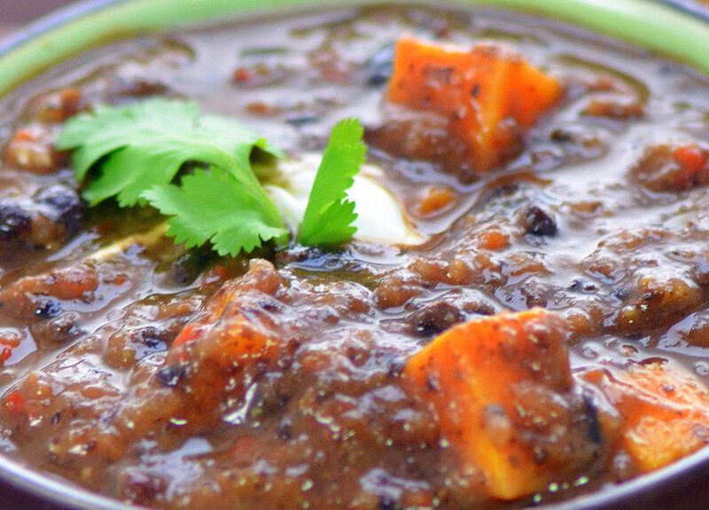 Close-up of Black Bean and Sweet Potato Soup with a sprig of flat-leaf parsley