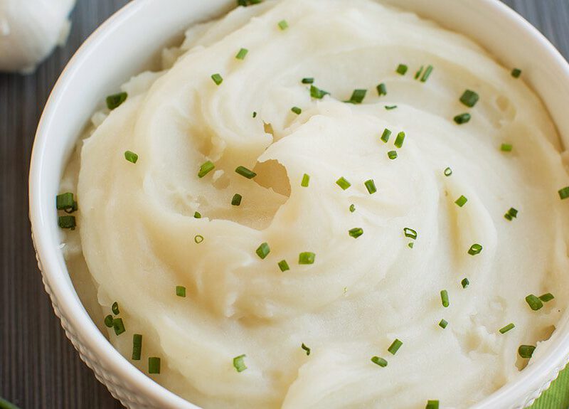 Vegan Mashed Potatoes in a white bowl with a garnish of chives