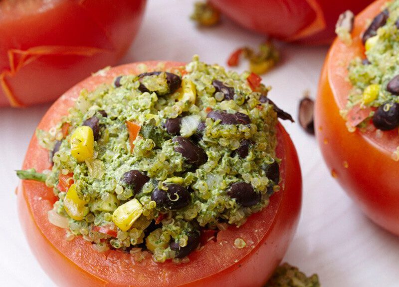 A close-up shot of two Quinoa-Stuffed Tomatoes with Spicy Cilantro Pesto on a white counter