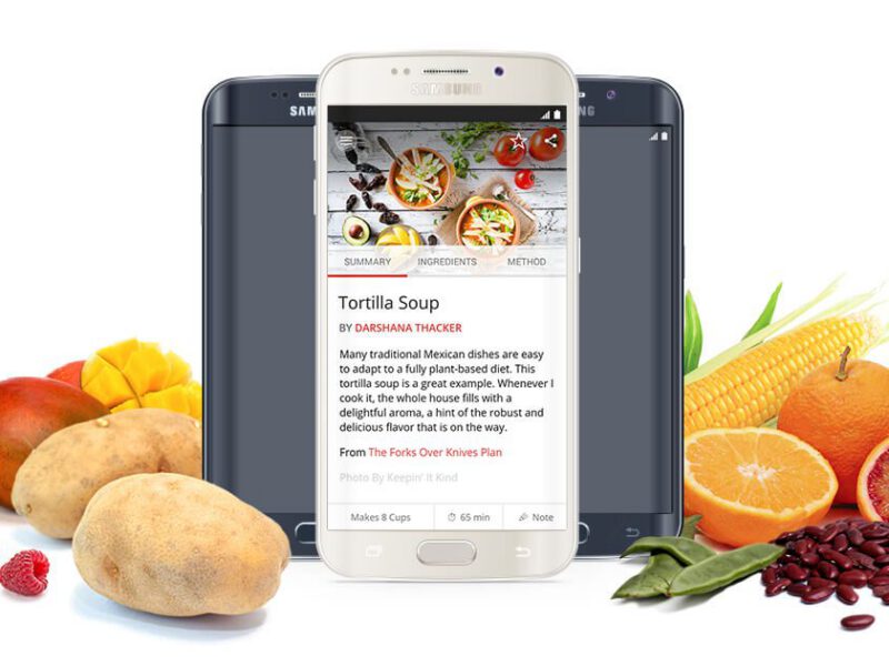 Mobile android phone displaying the Forks Over Knives recipe app, with fresh fruits and veggies to the side