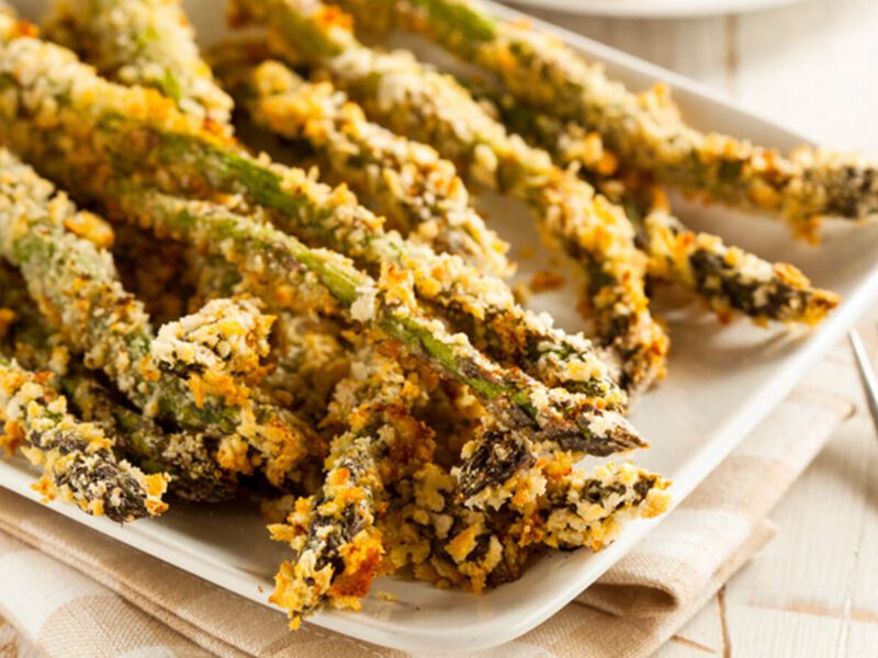 Herb-Crusted Asparagus Spears on a white serving platter with a fork to the side