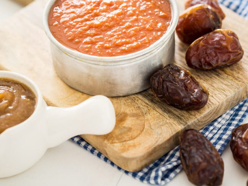 Easy Date Barbecue Sauce on a wooden chopping board with dates and a small jug of date paste