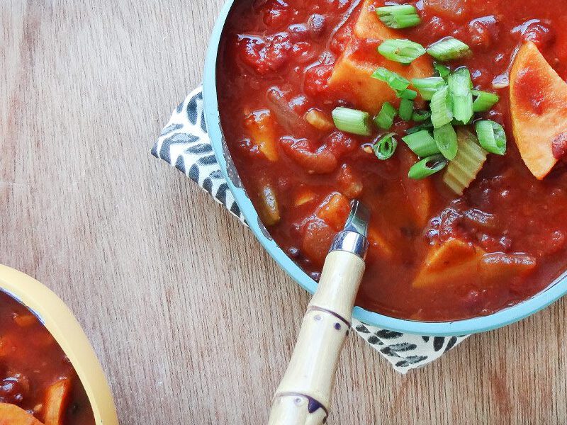 Two bowls of Smoky Chili with Sweet Potatoes garnished with sliced green onions