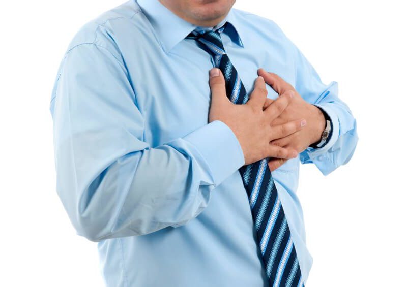A man in a business shirt clutching his shirt
