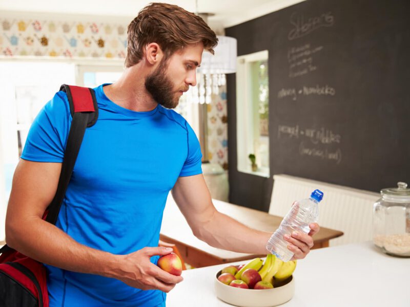 Man Wearing Gym Clothing Choosing Fruit From Bowl