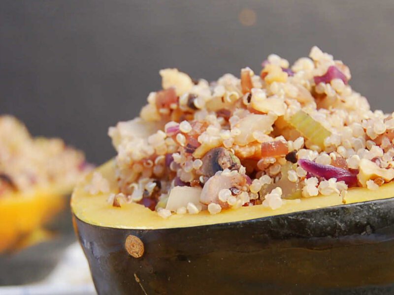 Easy Stuffed Acorn Squash on a chopping board with sprigs of rosemary. Another plate of squash is faded into the background