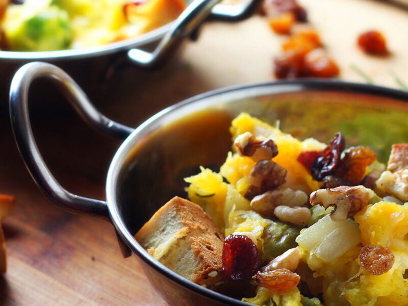 One-Pot Squash and Brussels Sprouts Panzanella with Dried Cherries on a wooden chopping board with croutons