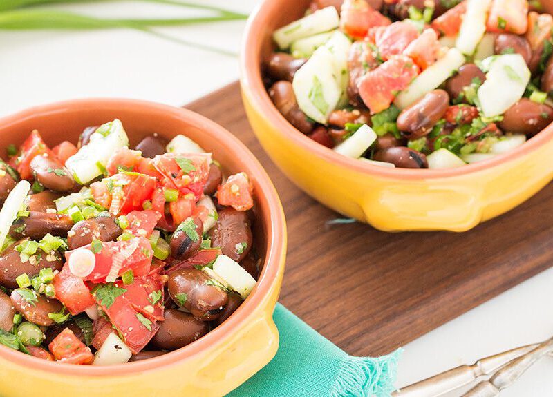 Two bowls of Fava Bean Salad on a wooden chopping board