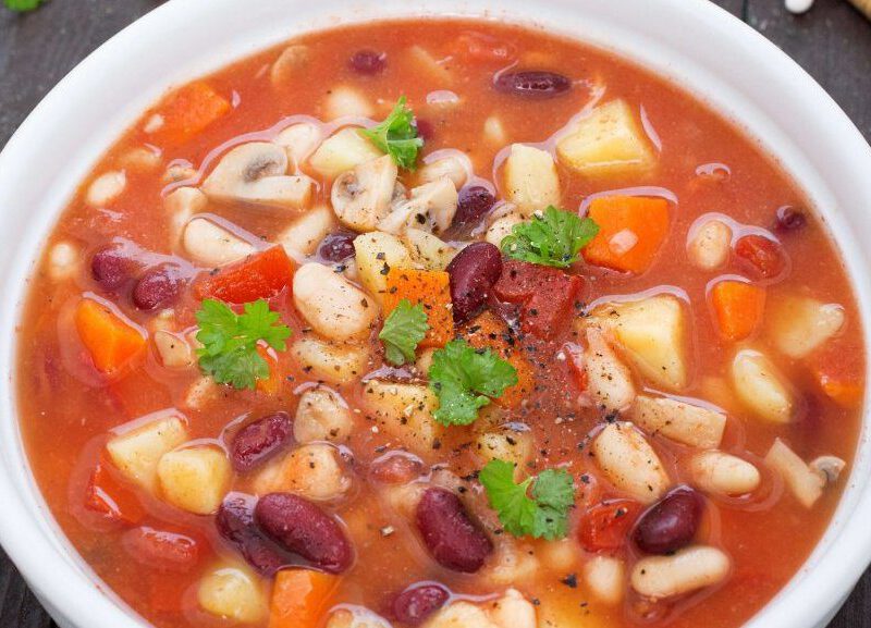 Mixed Beans and Root Vegetable Stew in a white bowl on a dark wooden table top