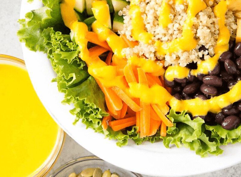 24-Carrot Gold Dressing in a small bowl next to a larger grain bowl drizzled with the dressing