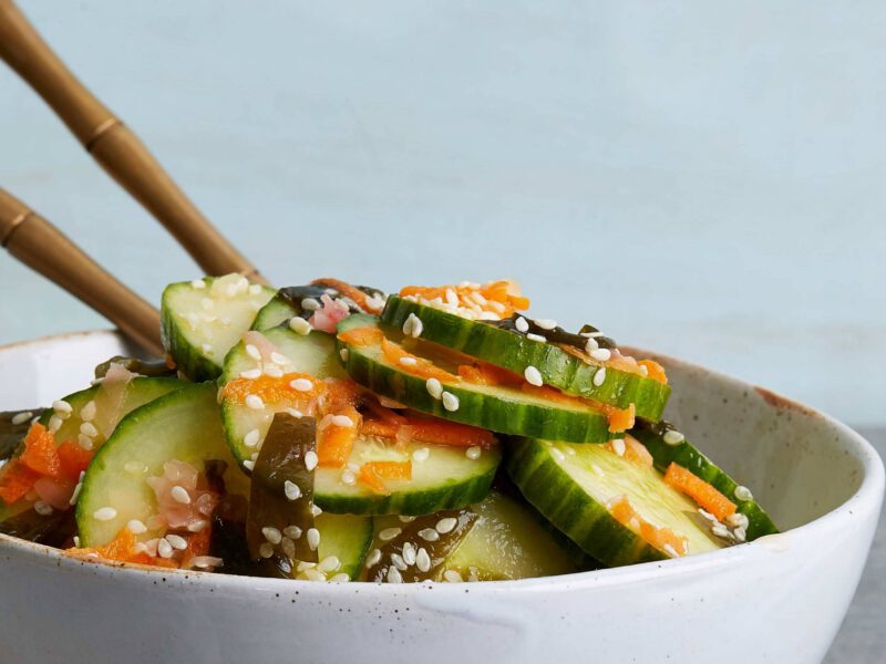 Asian Cucumber and Sea Vegetable Salad in a white bowl with chopsticks sticking out of the bowl