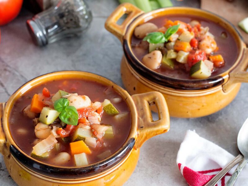 Two bowls of vegan minestrone on a table