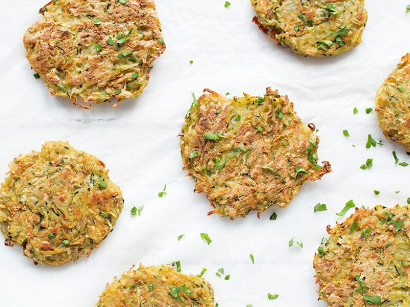Potato Pancakes on white baking paper on a white table with finely chopped flat-leaf parsley sprinkled throughout