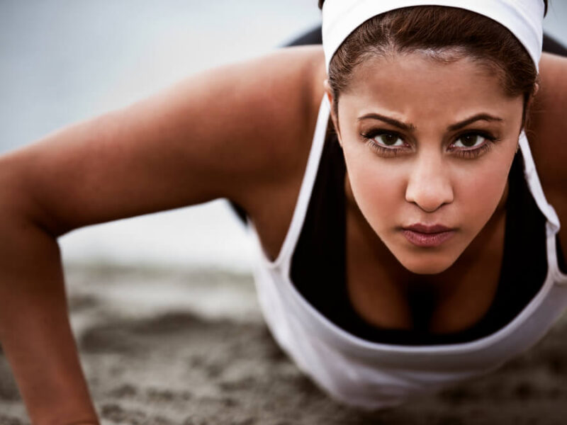 A young woman looking into the camera while doing a push up