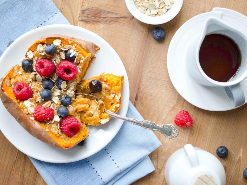 A baked sweet potato topped with oats and fresh berries