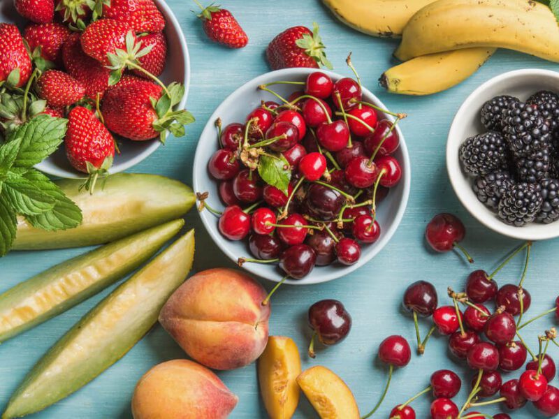 Healthy summer fruit variety on blue wooden backdrop