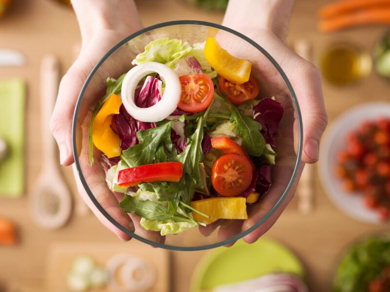 Hands outstretched holding healthy fresh homemade salad