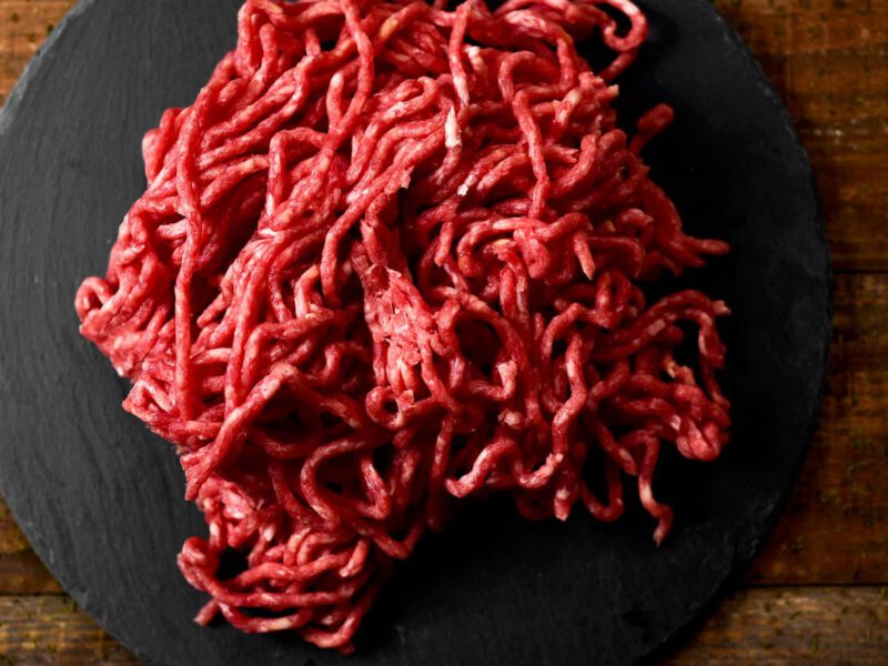 A pile of worm-like raw ground beef on a black plate