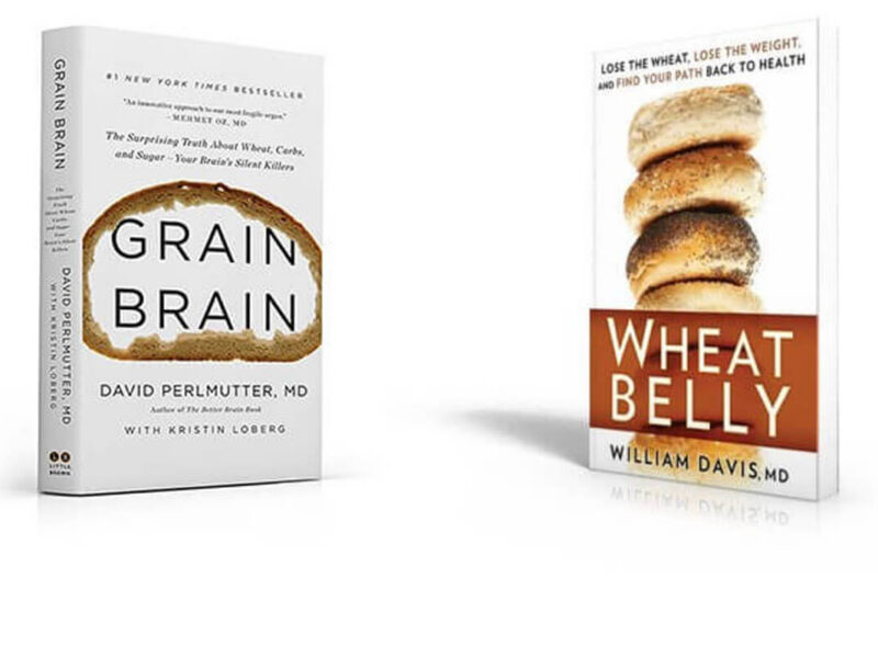 Two books stand up on a white background: "Grain Brain," and "Wheat Belly"