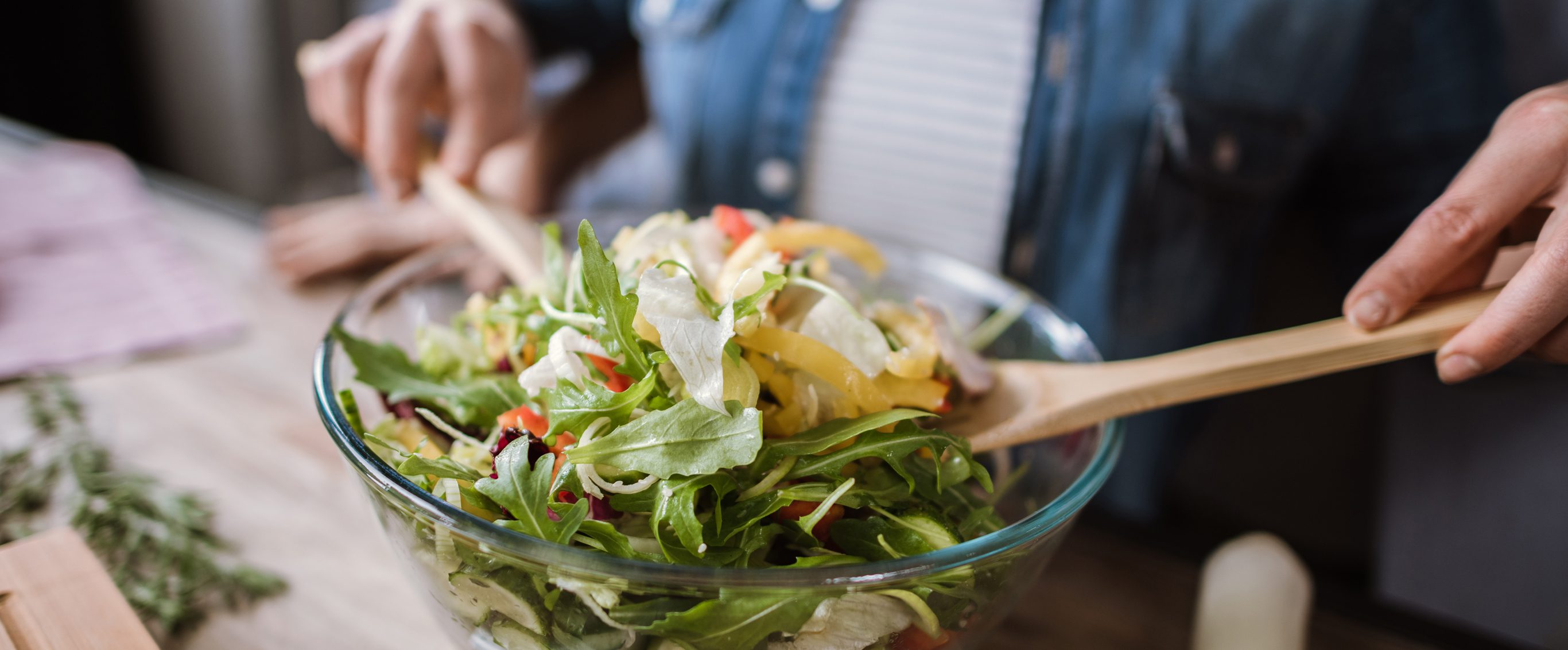 Woman tossing salad with light dressing