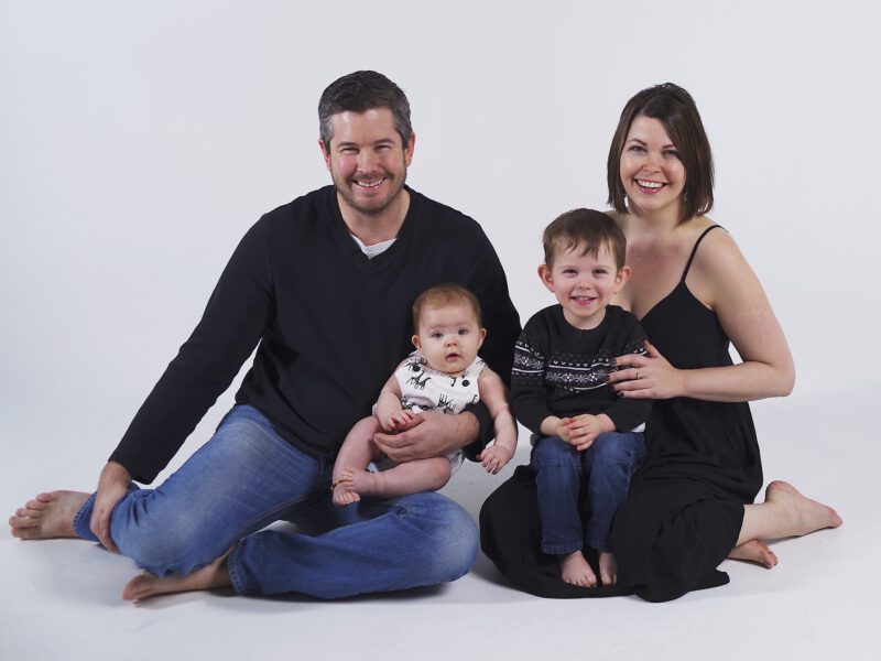 Jennifer Sinyerd and her husband sitting on the ground with their two young children