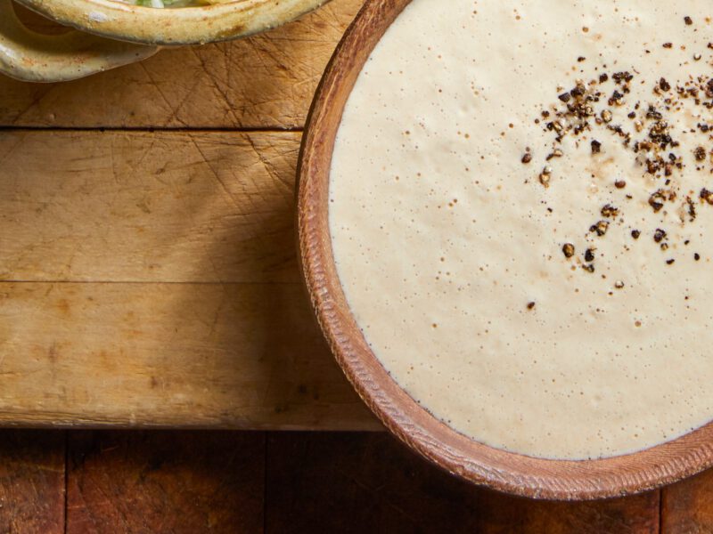 Tahini Dipping Sauce in a small handmade ceramic bowl on an old wooden chopping board