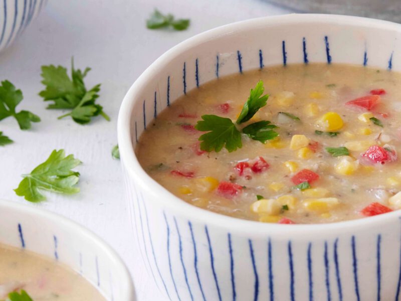 Easy Vegan Corn Chowder in a rustic white bowl with blue stripes