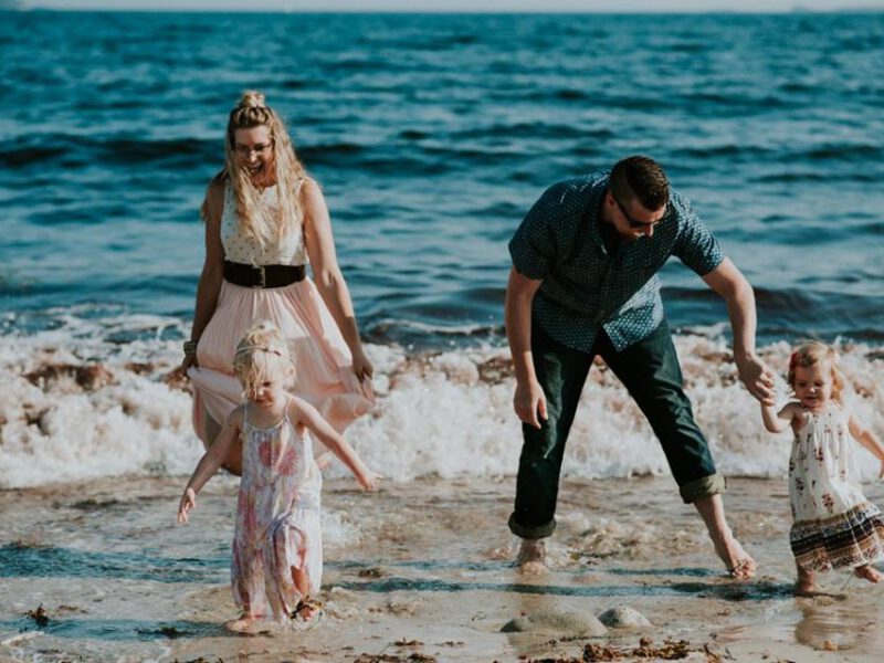 Chris Noel with his wife and two children, playing in the surf at the beach