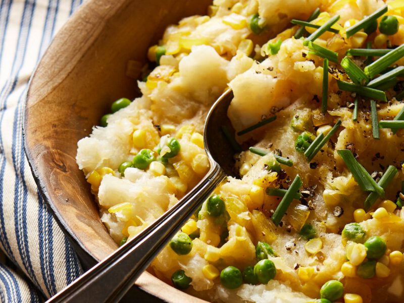 A wooden serving bowl of Yuca Mash with Corn and Peas
