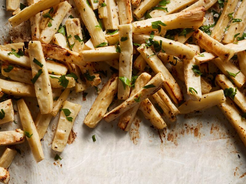 Baked Yuca Fries on sprinkled with chopped fresh herbs, on parchment paper