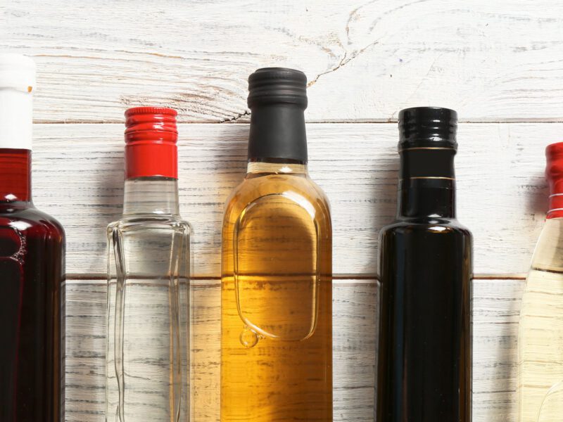 Seven unlabelled bottles of various vinegars.