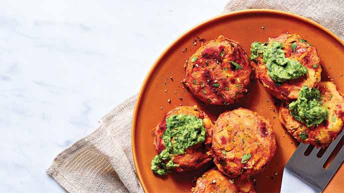 Vegetable Fritters on an orange plate topped with green goddess sauce