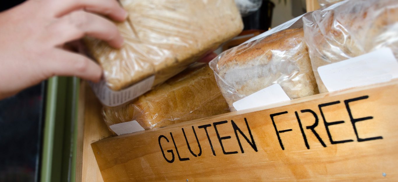 hand selecting gluten-free bread loaf off a wooden shelf