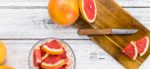 Grapefruit shown sliced into small pieces on a cutting board with a knife