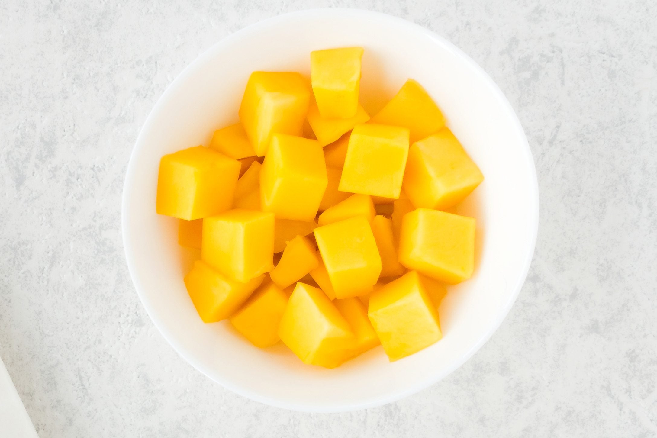 Top view of mango cubes in white bowl.