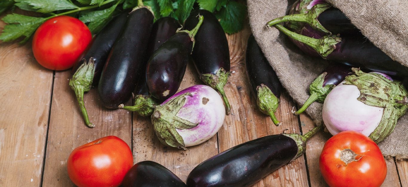 szereg warzyw psiankowatych – w tym bakłażan, pomidor – na drewnianym stole
