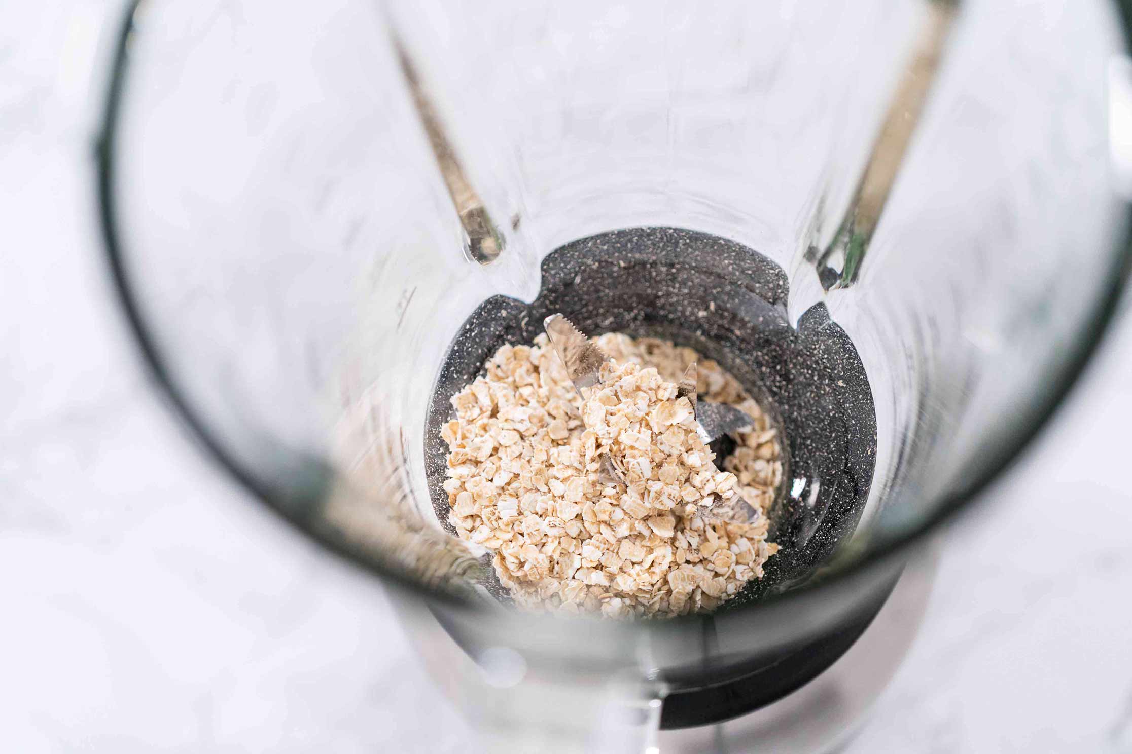 A top down view of some oats in a blender before being ground into oat flour