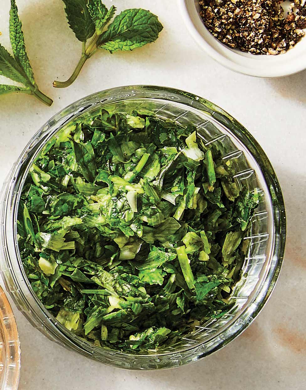 A green, herby oil-free smashed garlic and herb dressing shown in a small glass bowl
